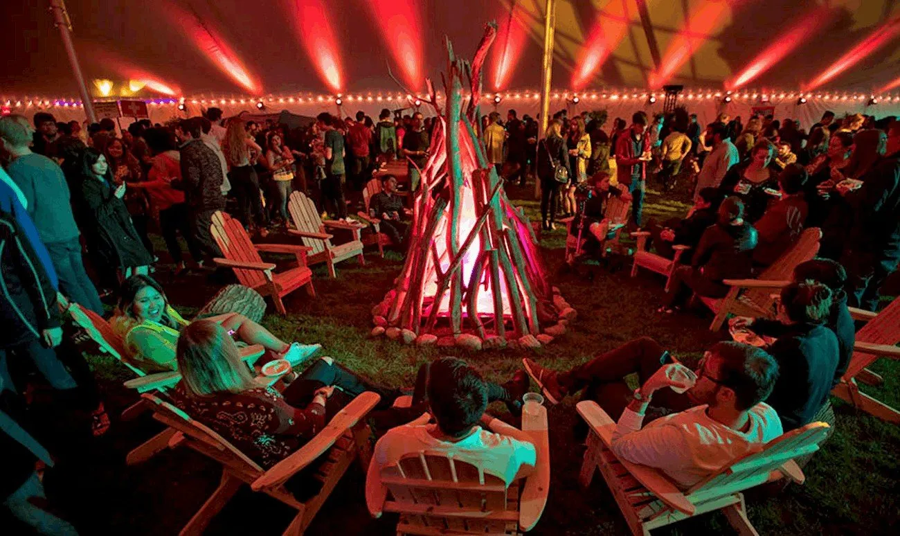 Wide view of a large event room with a central lit fire sculpture