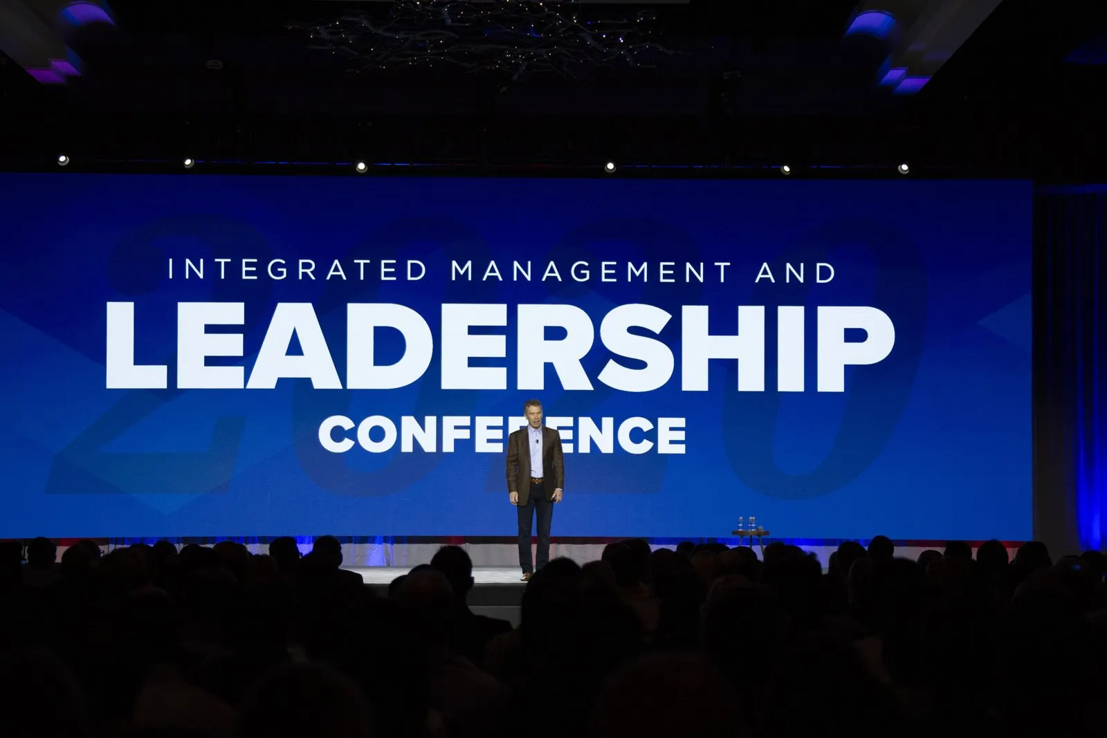 Integrated Management and Leadership Conference screen with a presenter on stage