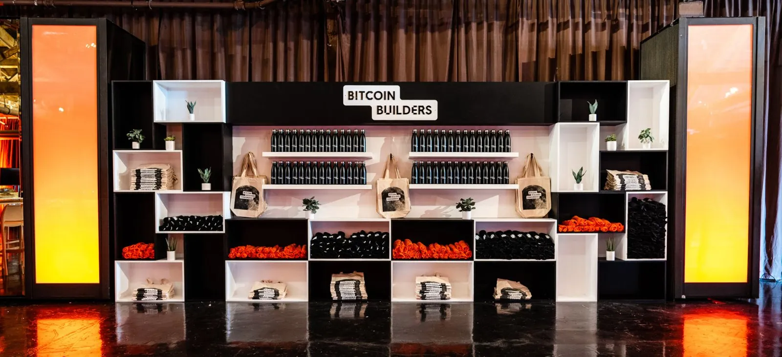 Branded stage set with lit panels and shelving at the Bitcoin Builder Conference 2023