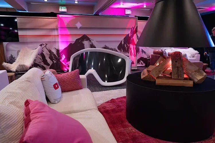 Lounge seating around a black fire pit in front of a mountain mural at the YouTube lounge
