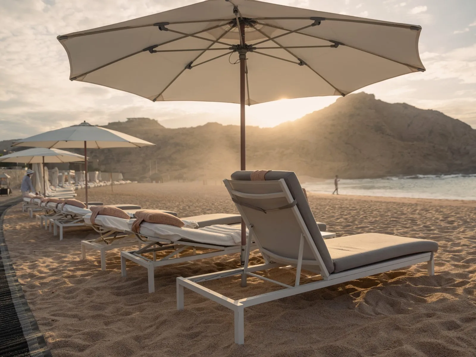 Beach lounge chairs and a large umbrella at sunset at a retreat