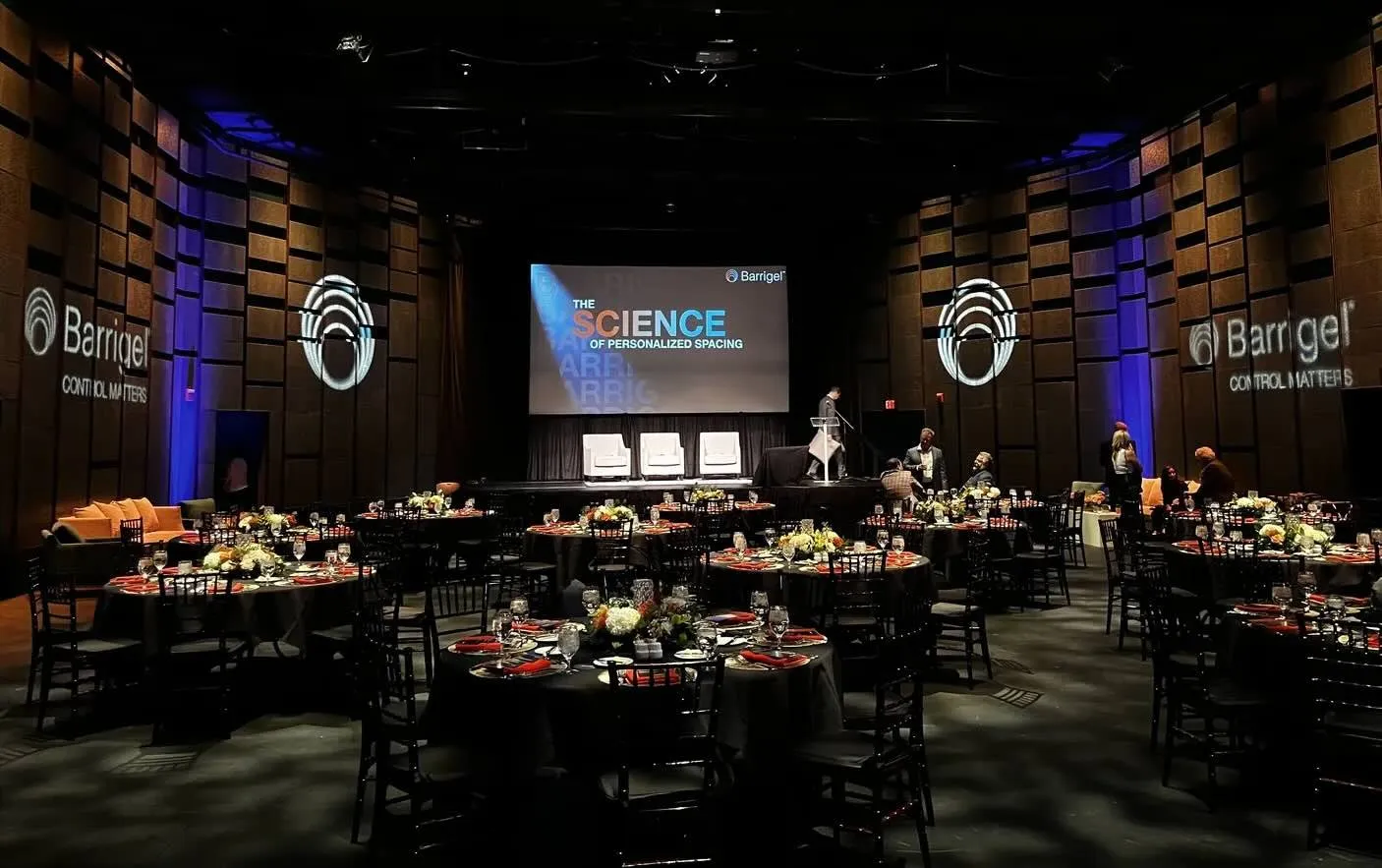 Corporate dinner with round tables and a stage screen