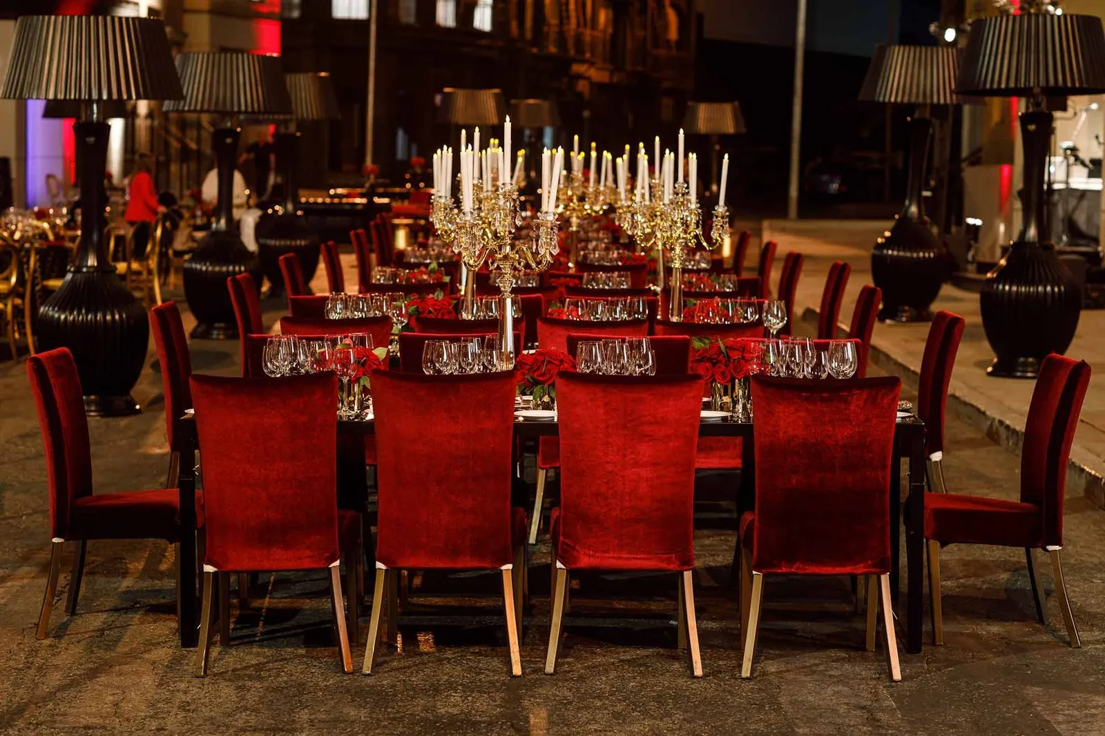 Long dining tables with red chairs and candle centerpieces in a large hall
