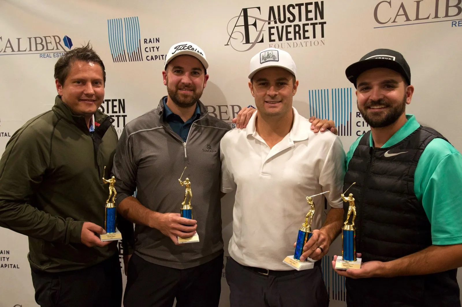 Golfers holding trophies at the Caliber golf tournament