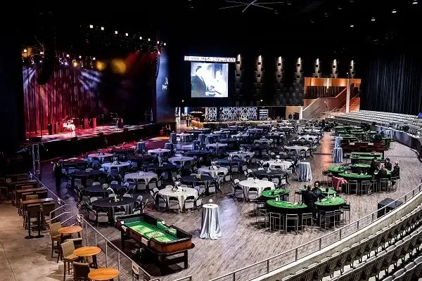 Event hall with round tables, a stage and game tables set up for a corporate evening