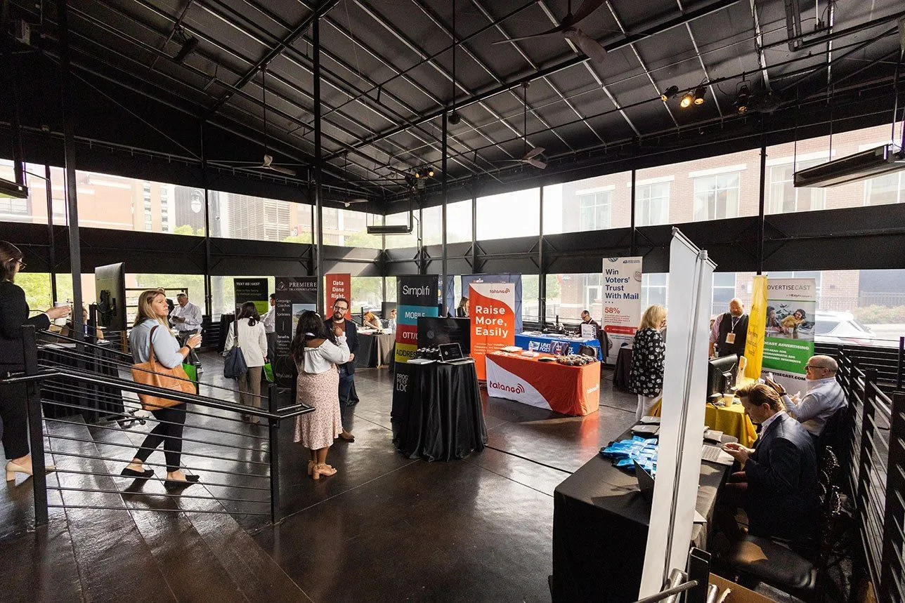 Attendees browsing vendor booths at a trade event in an open industrial space