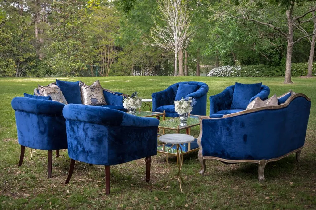 Velvet armchairs arranged on a tree-lined lawn for retreat downtime