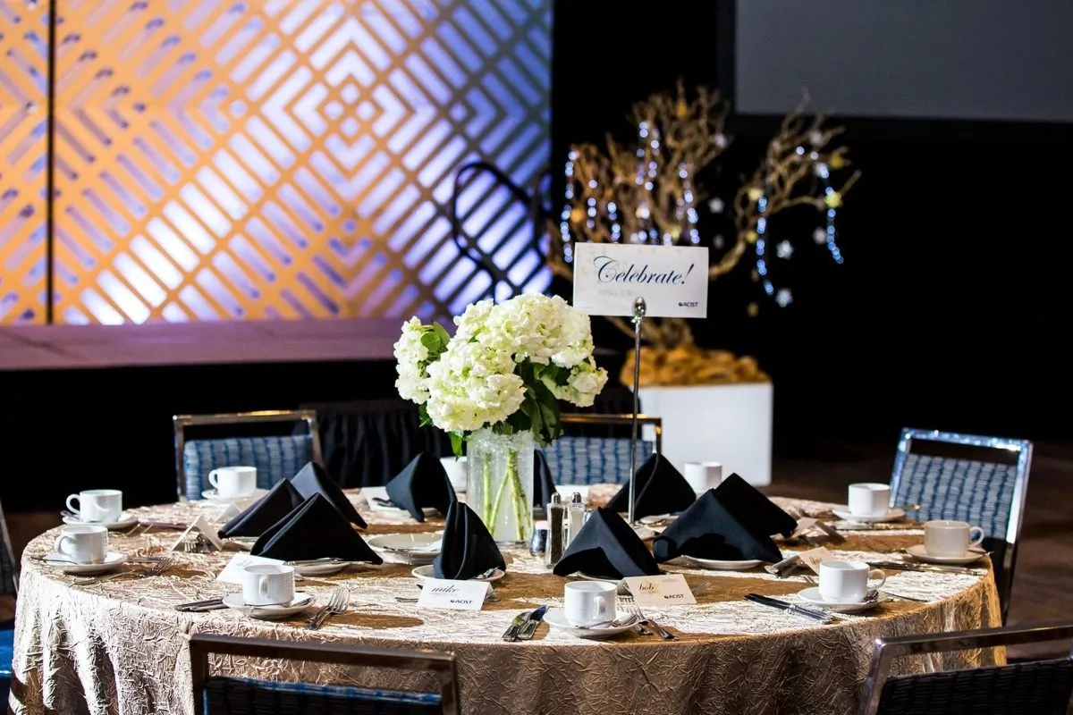 Round table with a floral centerpiece in front of a lit stage panel