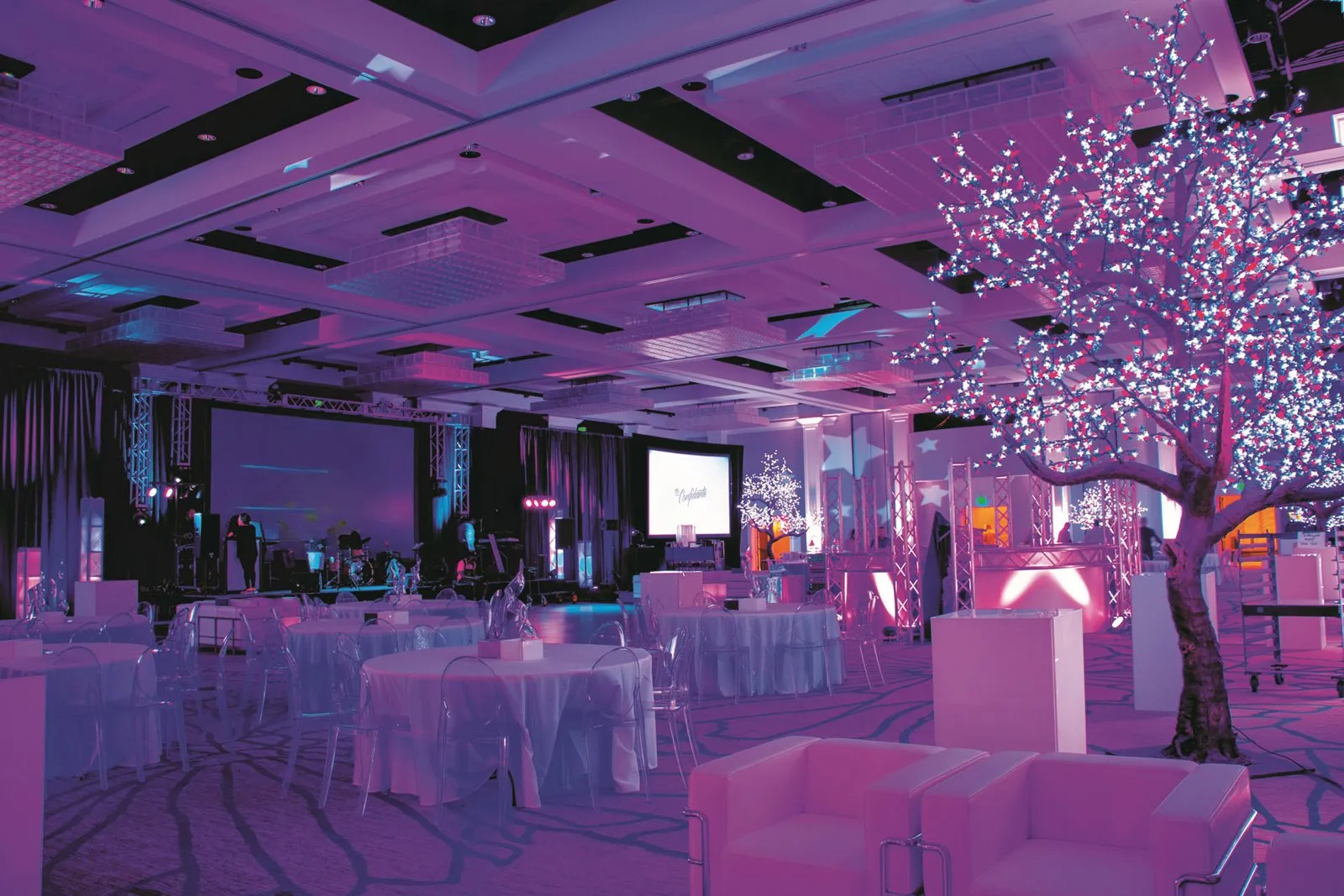 Reception room with pink and blue lighting, lounge seating and a lit tree