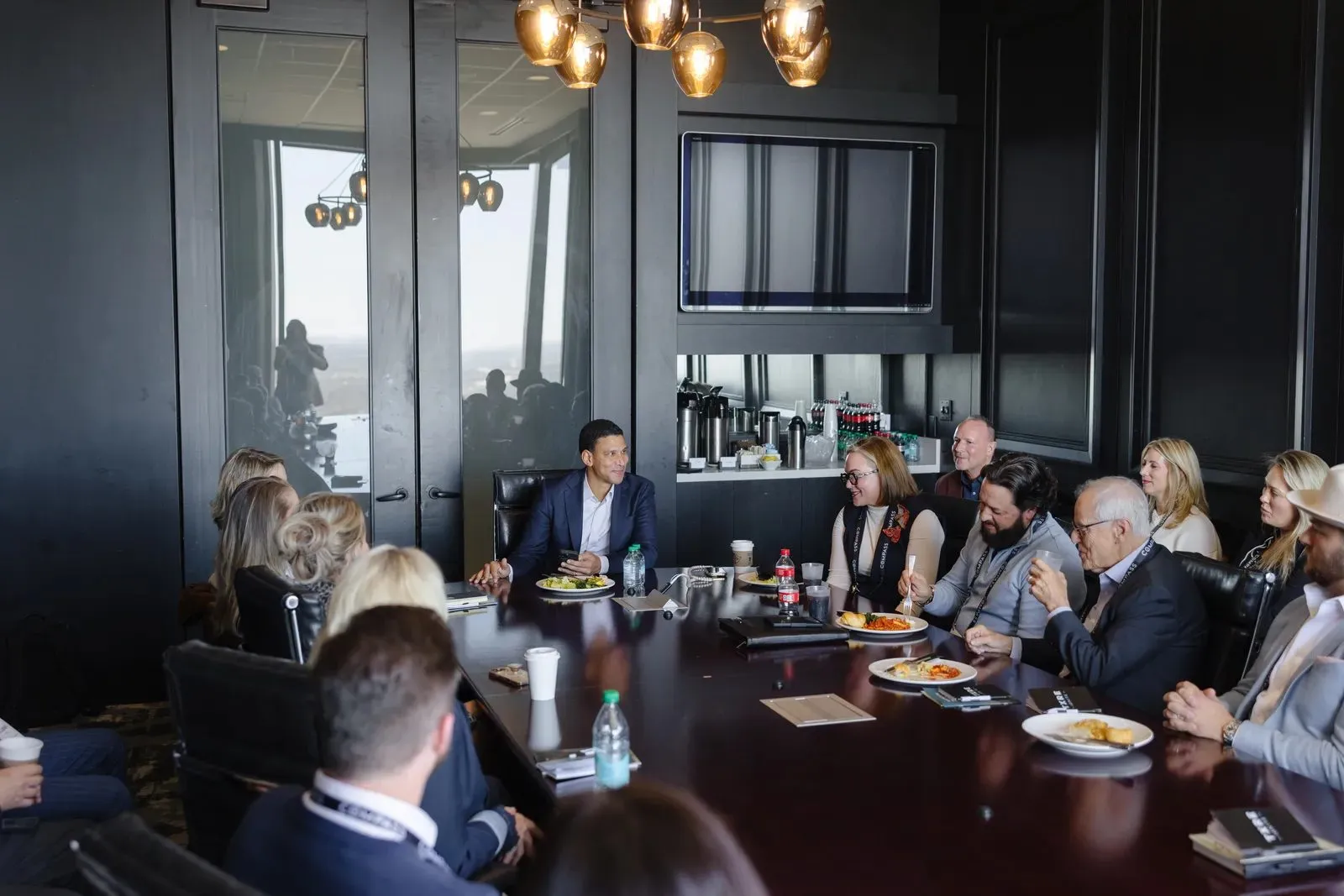 Guests seated around a long table in a dark paneled meeting room