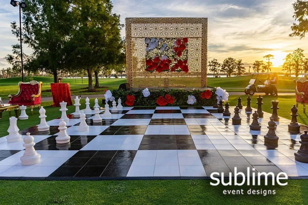 Lawn set with a giant chess board and a floral backdrop at golden hour