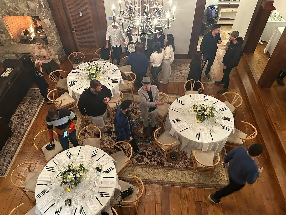Round dinner tables with white florals under a chandelier, seen from above