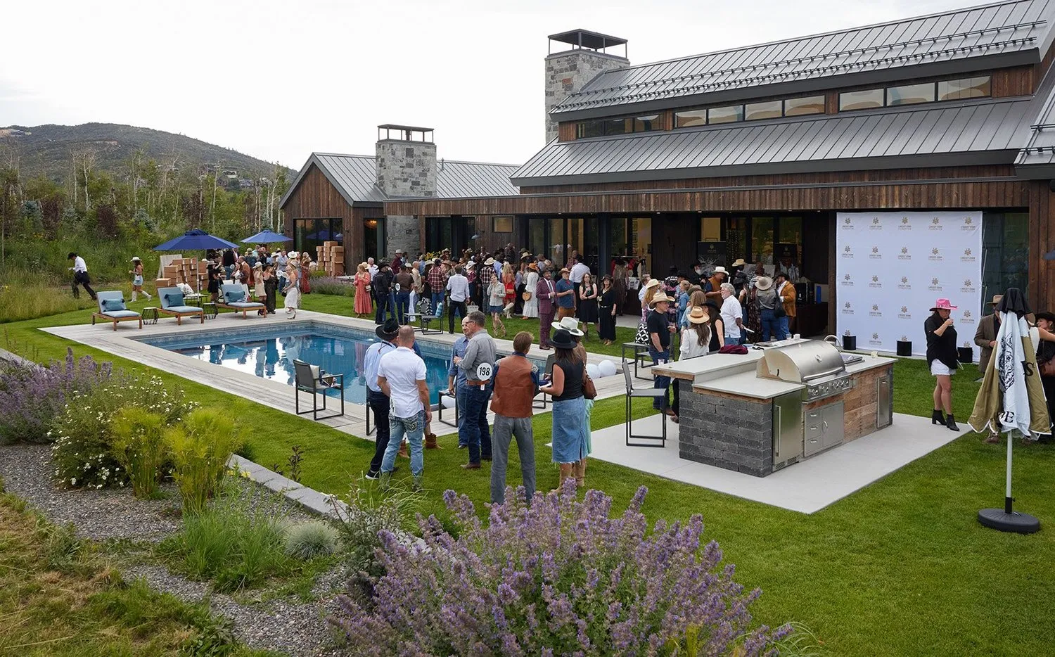Guests at an outdoor poolside reception beside a mountain home
