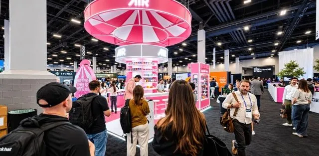 Attendees at a trade show booth with a pink carousel structure