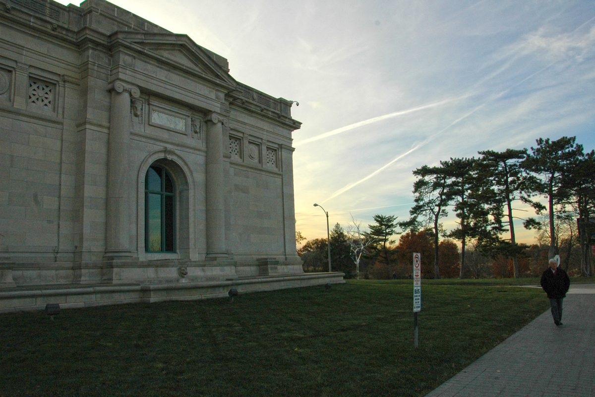 A stone wall of the Saint Louis Art Museum beside a lawn in Forest Park.