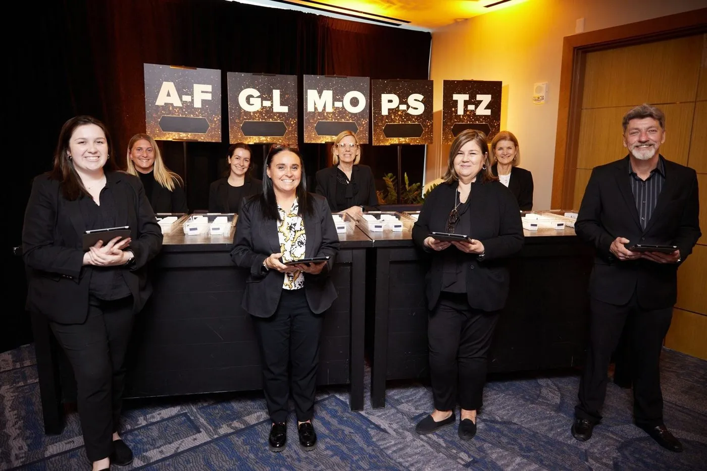Registration team standing behind alphabetical check in desks