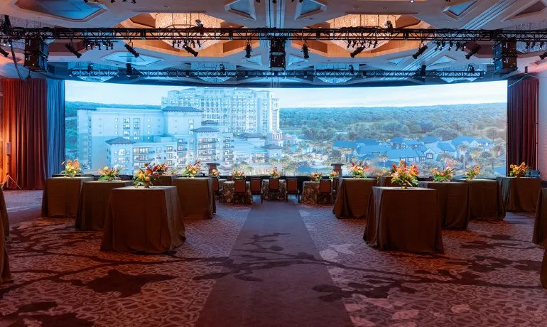 Dinner tables set in front of a large harbor scene display for an executive meeting