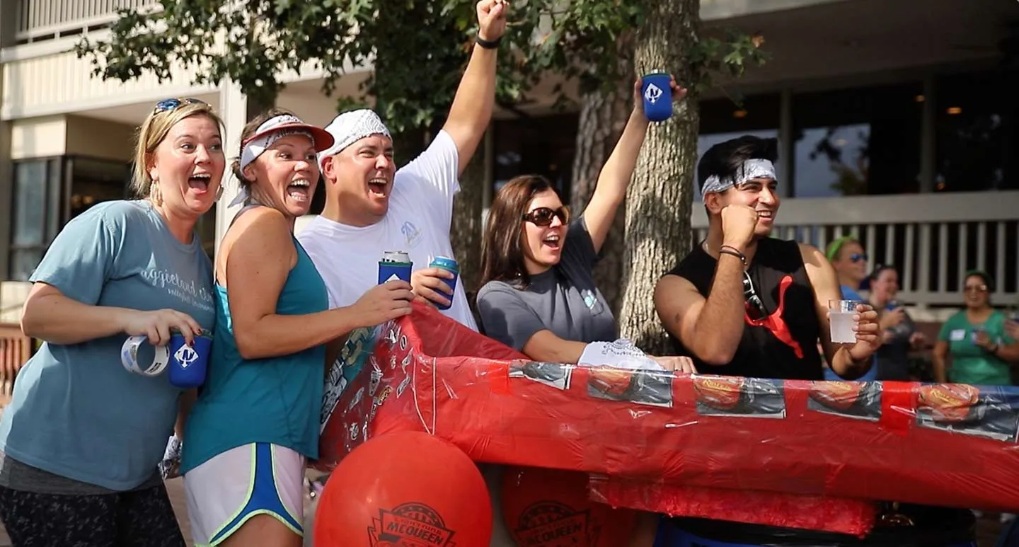 Team members toasting at a red covered table at a team event