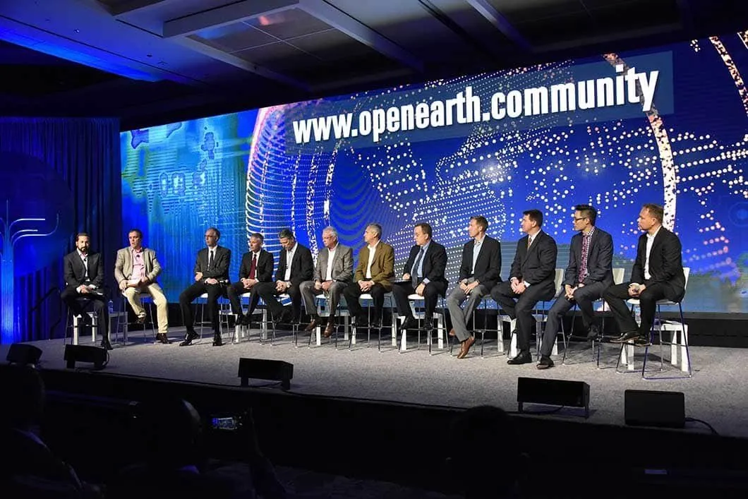 Panel of speakers on stage in front of a large screen