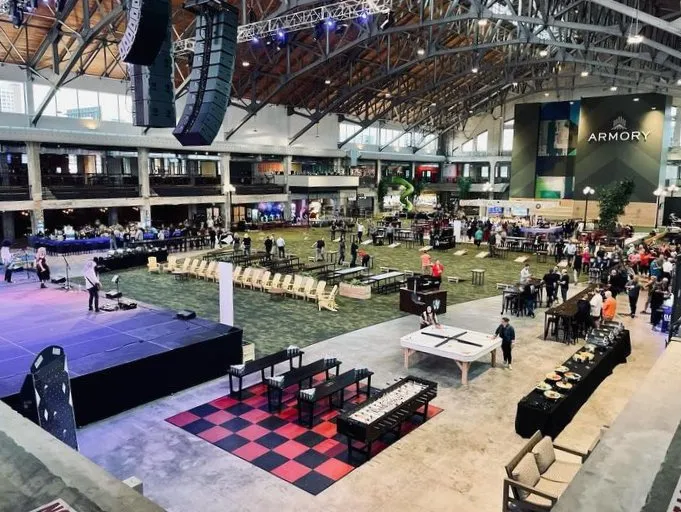 Large exhibition hall set with a stage, seating areas and a checkered dance floor