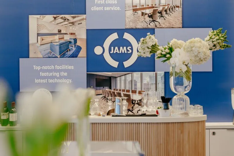 Company booth display with a brand sign and floral accents