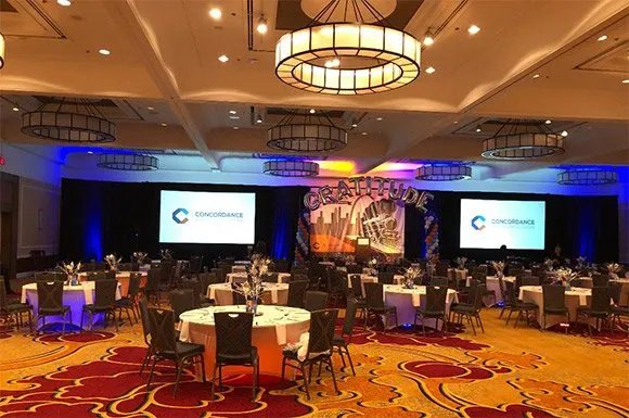 Banquet ballroom with round tables and two screens set for a healthcare conference