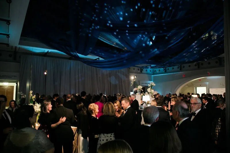 Crowd of guests under a dark starlit ceiling at an evening event