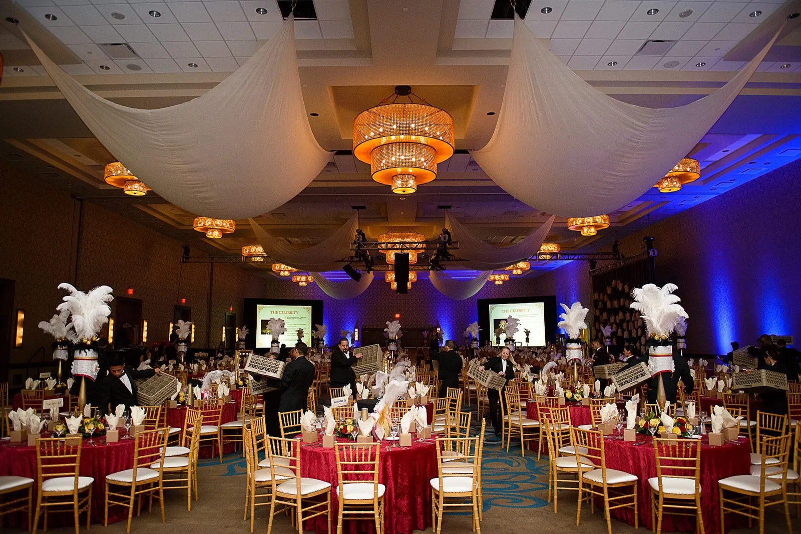Ballroom set for a dinner with draped ceiling and uplighting