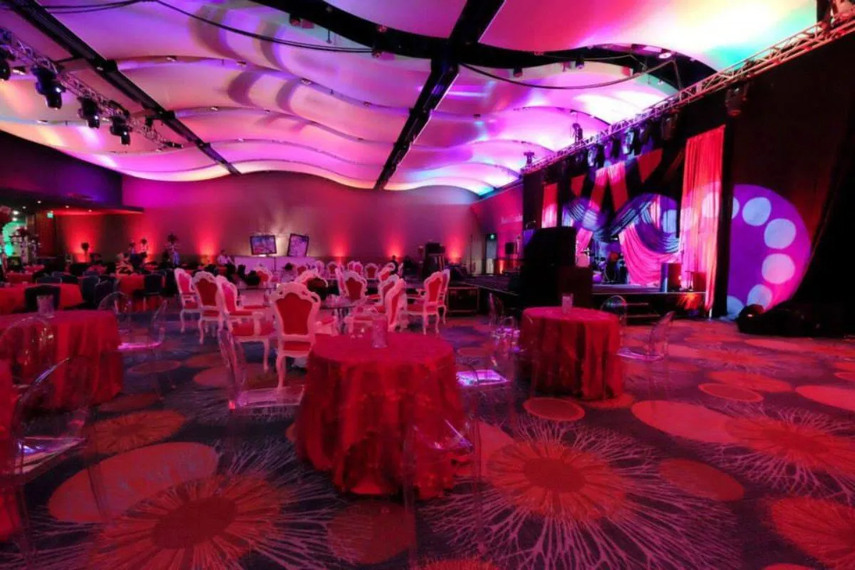 Ballroom set with red covered round tables and pink lighting
