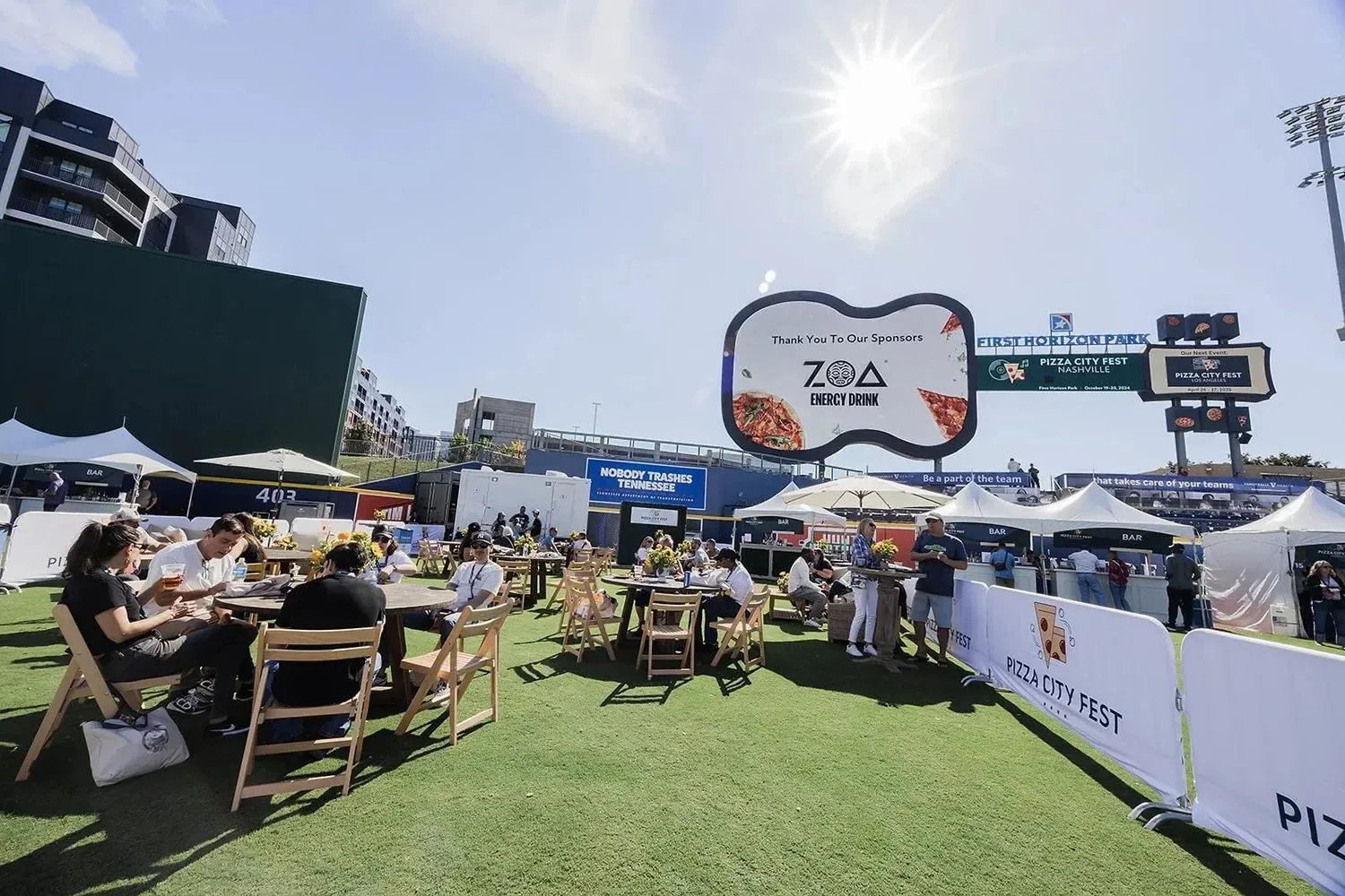 Guests at tables on a baseball stadium field during a group event