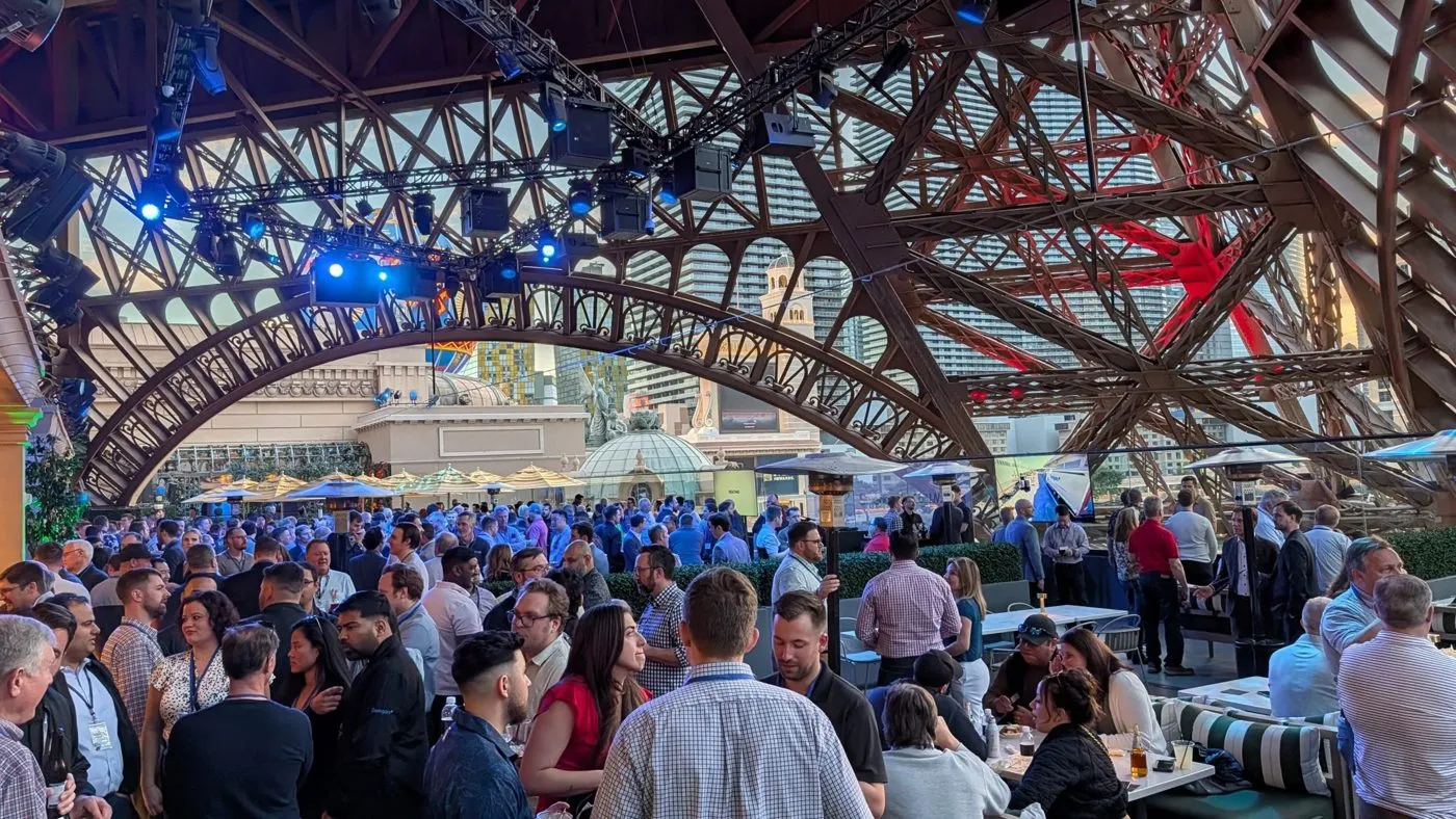 Crowd of guests at an outdoor evening event beneath a steel canopy