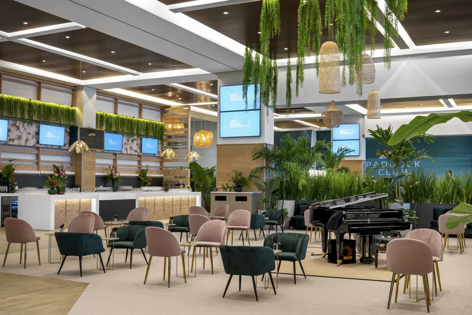Paddock Club lounge with a grand piano, dining chairs and hanging greenery