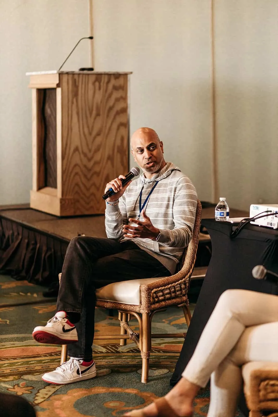 Speaker seated on stage with a microphone during a NOYO retreat session