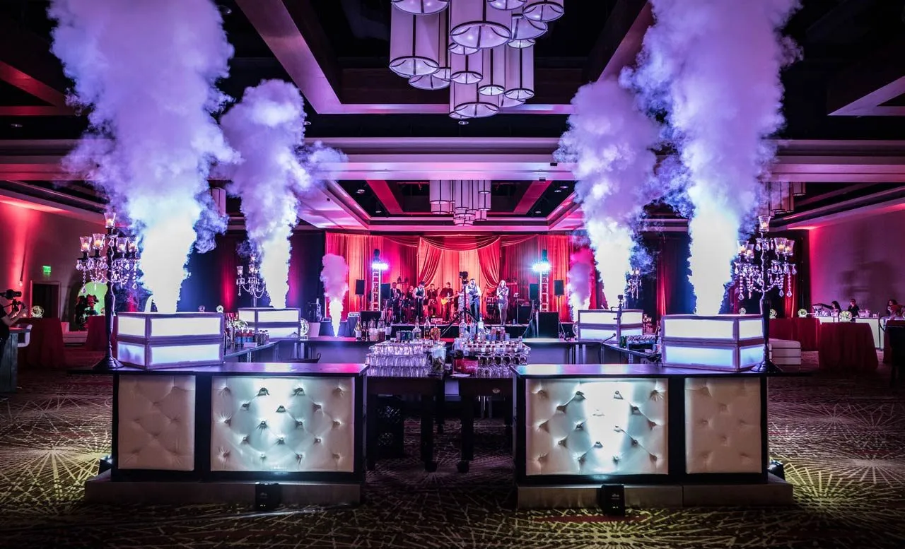 Bar with smoke cannons in a ballroom lit in pink and blue