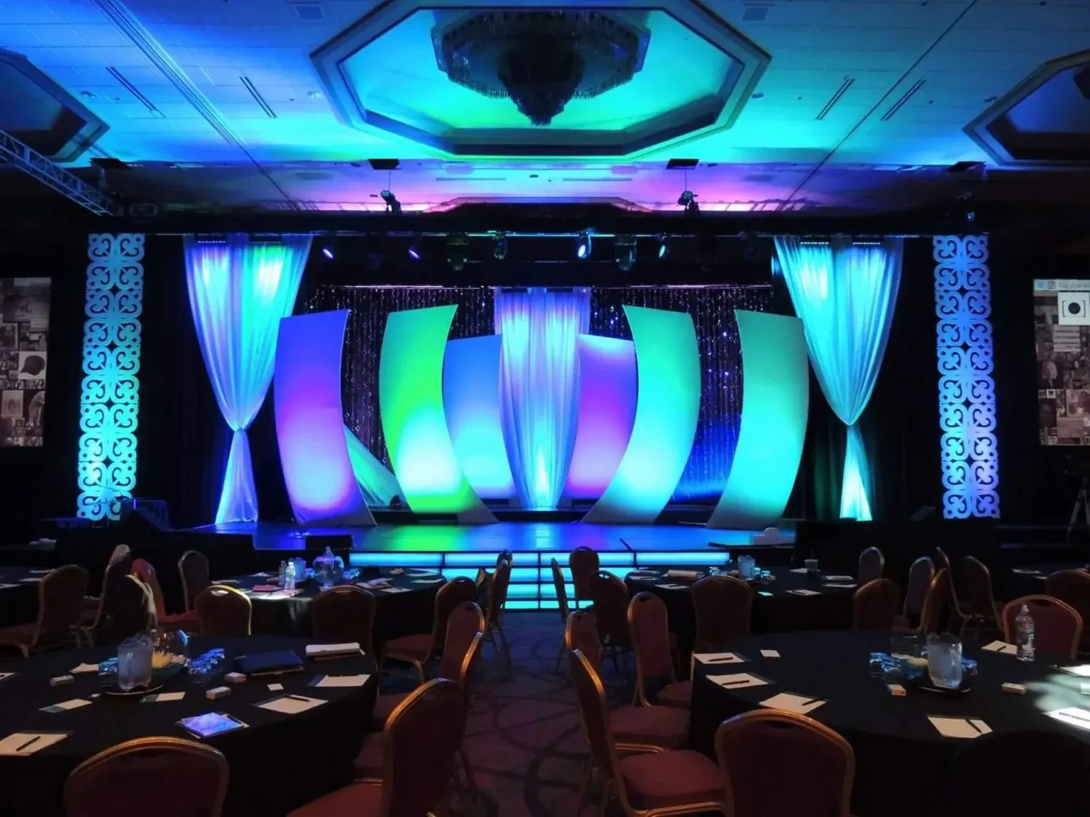 Stage with blue and green lighting and draped panels set for a corporate session