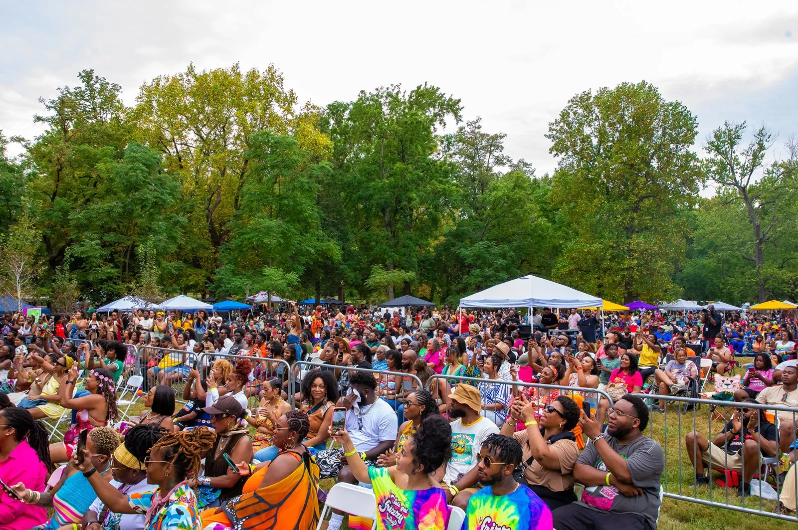 Large outdoor festival crowd under trees and tents