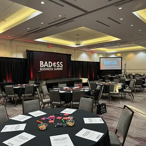 Conference room set with round tables and a stage screen for a business summit