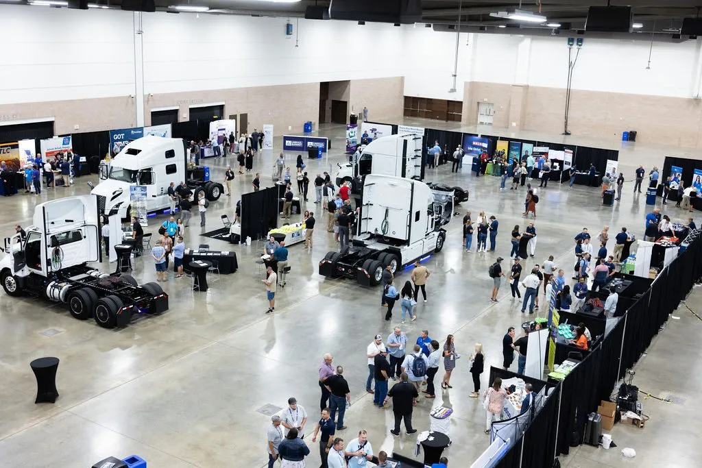 Overhead view of an exhibit hall with trucks and booths at an industry summit