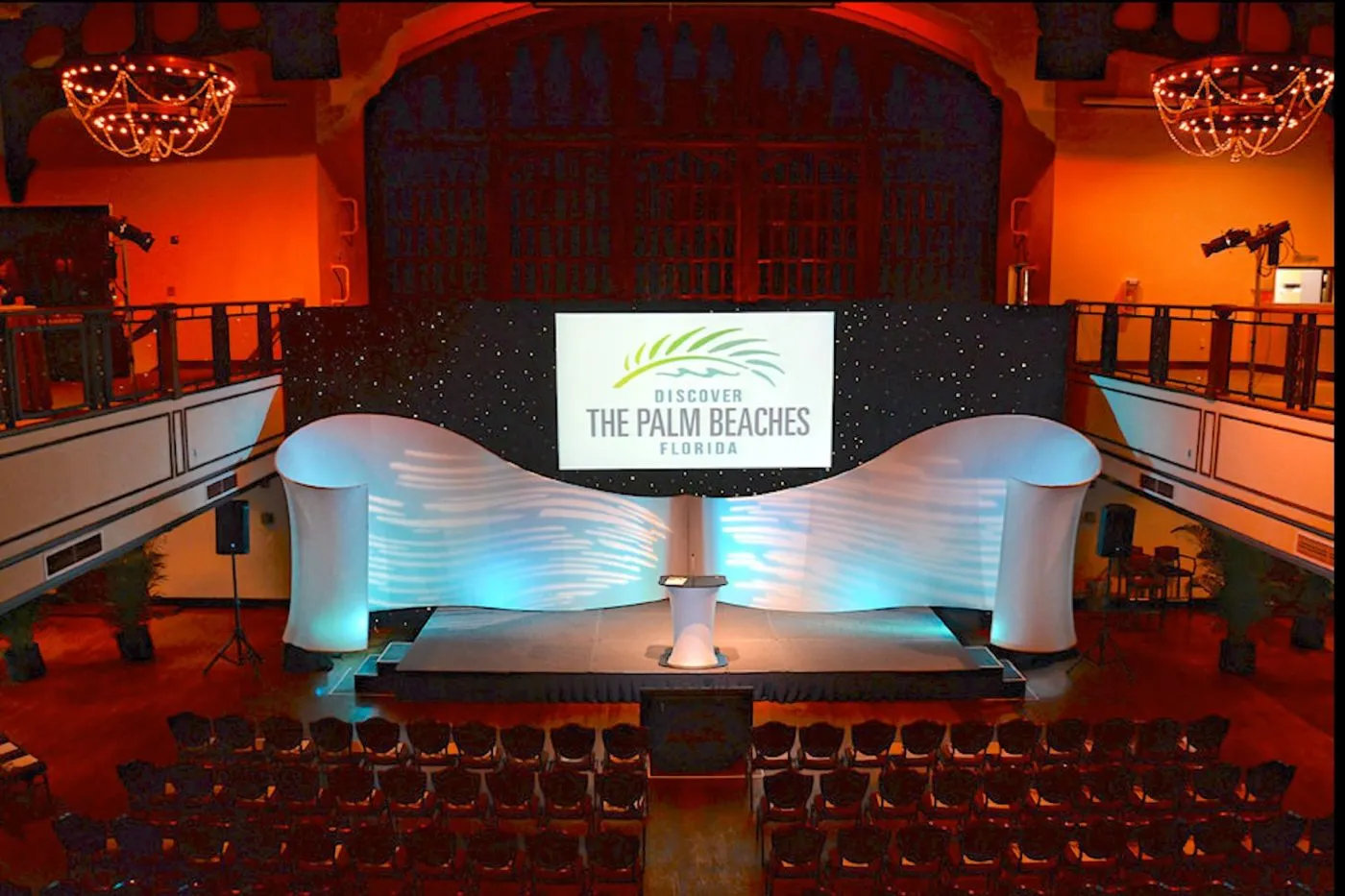 Ballroom stage with a curved white set and warm architectural lighting