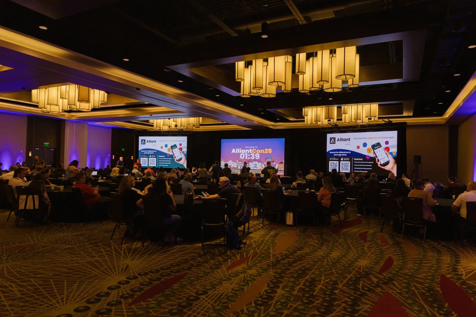 AlliantCon 2025 general session with a three-LED-wall stage