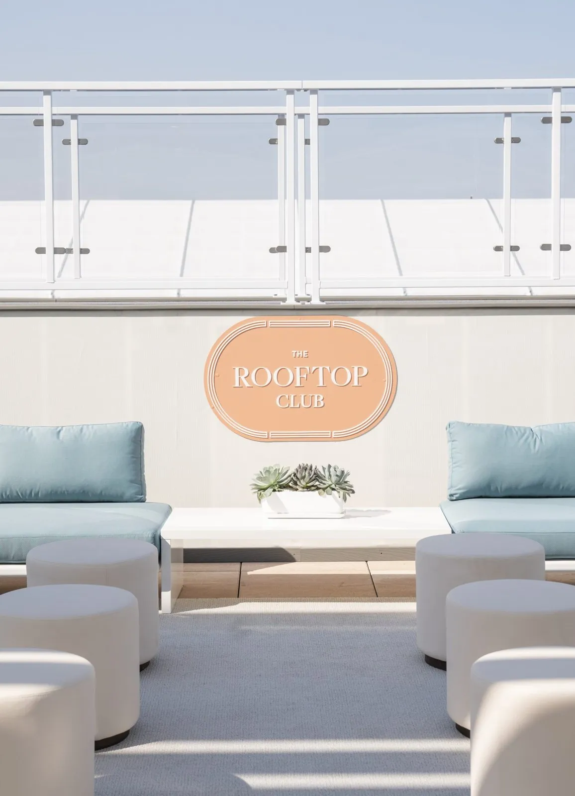 Rooftop lounge with white seating and an oval sign at the Paddock Club