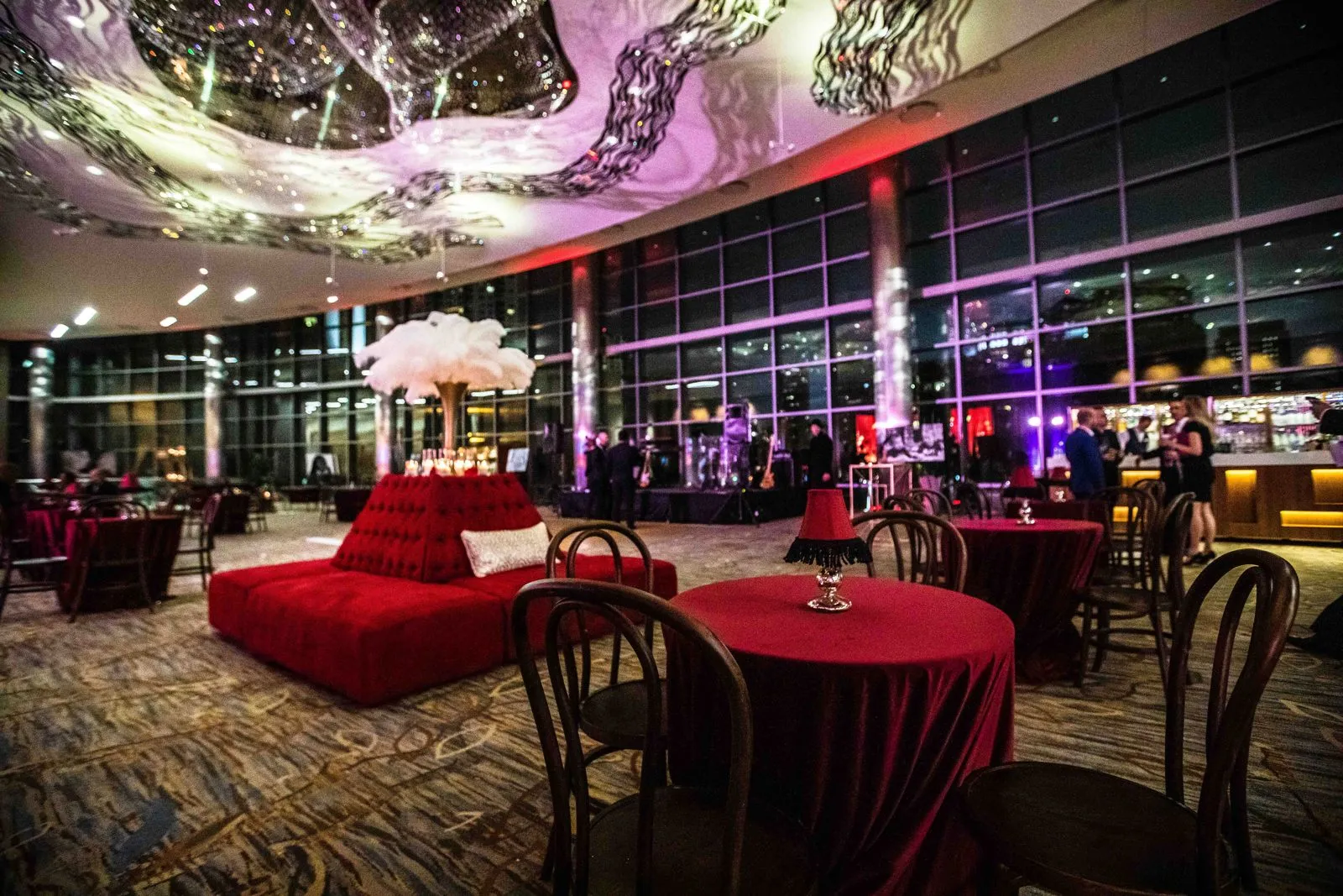 Lounge seating and round tables set for an evening reception with a city view