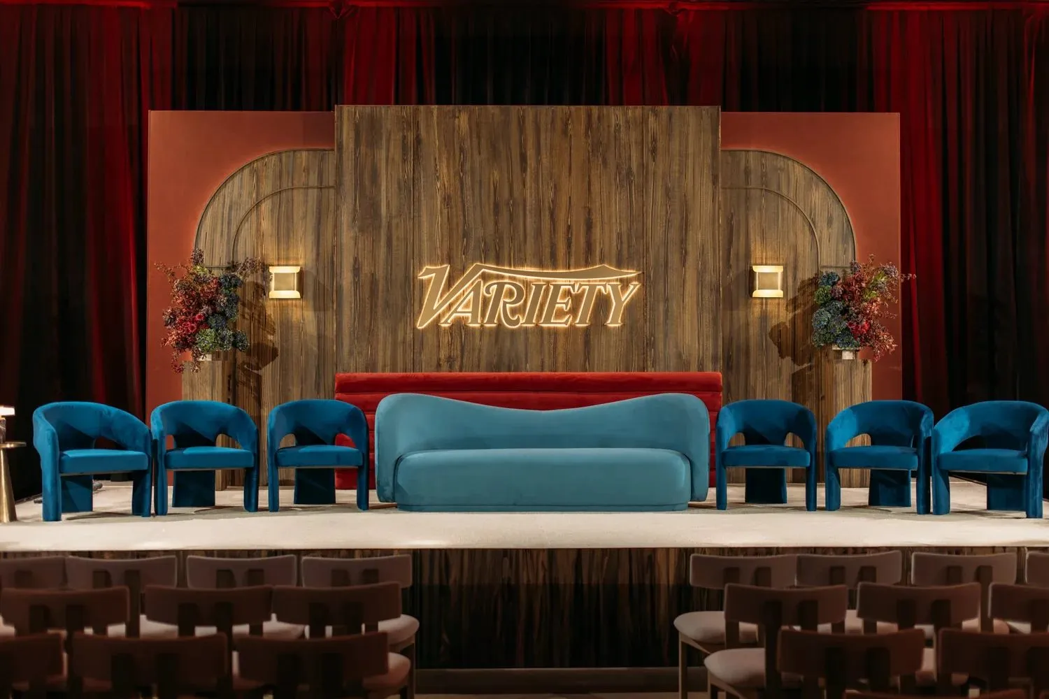 Summit stage with a lit wooden backdrop, sofas and armchairs