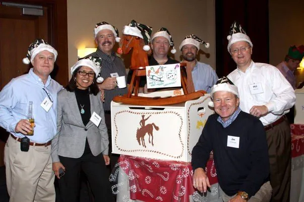 Colleagues in festive hats around a themed company party display