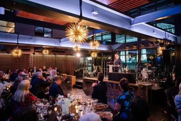 Corporate dinner under starburst chandeliers with a speaker at the front of the room