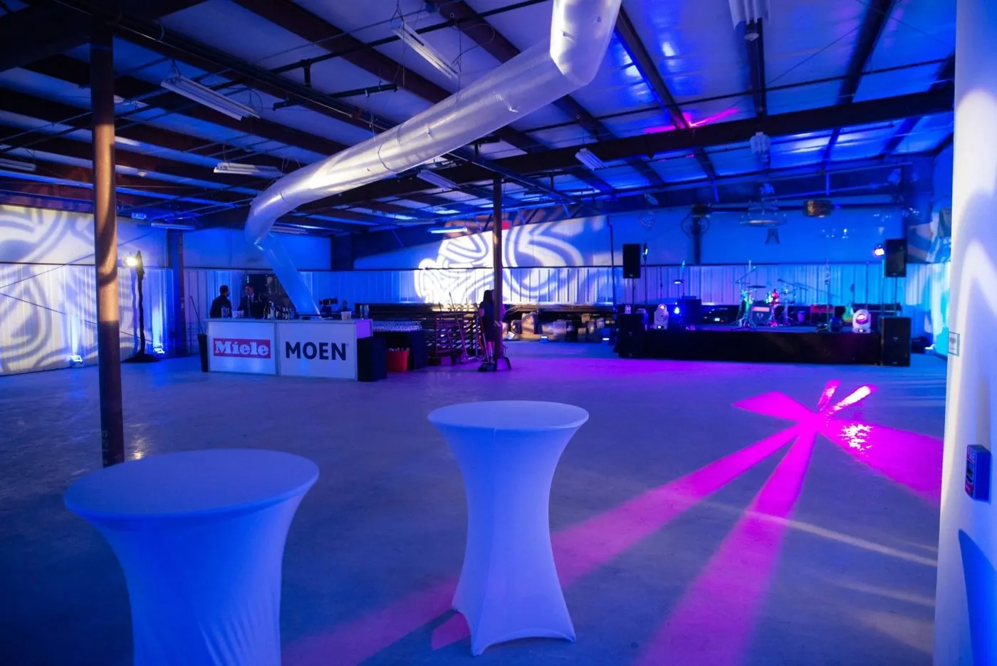Venue set with lit high top tables for an evening corporate event