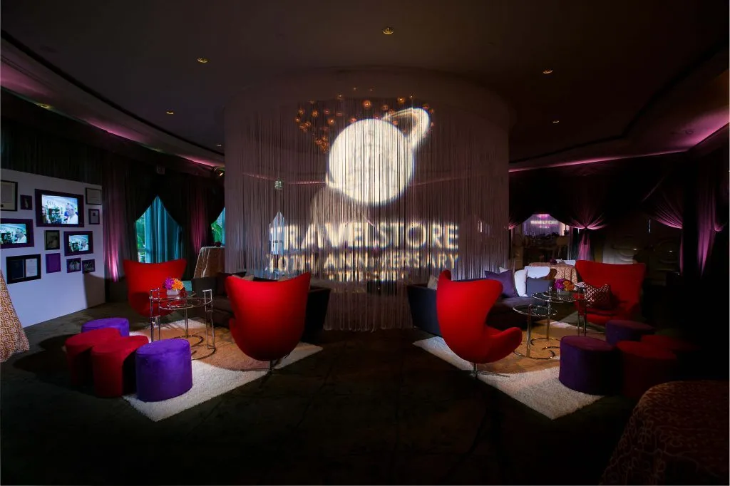 Dark lounge with red seating and a projected sign on the wall