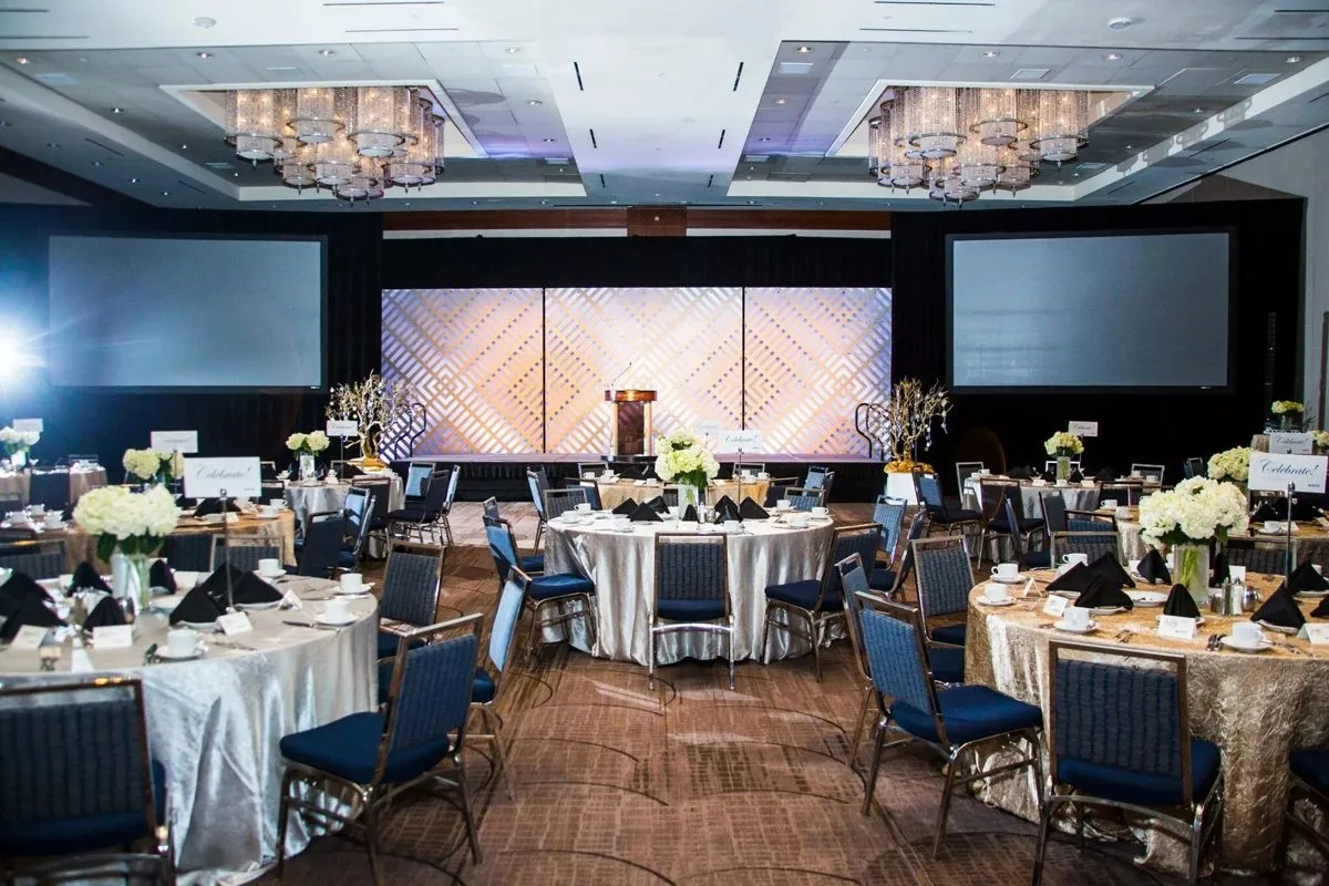 Ballroom set with round tables and a lit stage backdrop