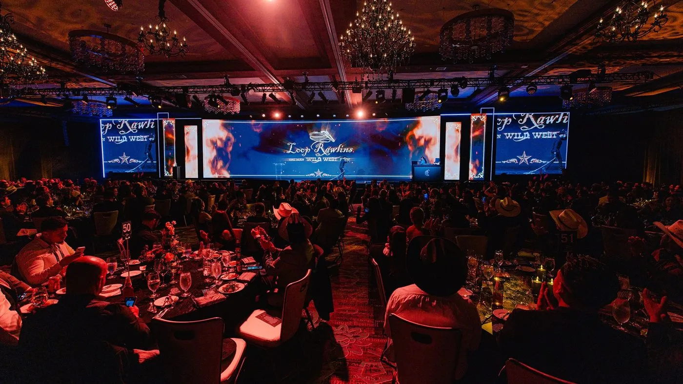 Ballroom dinner with a stage, screens and seated guests