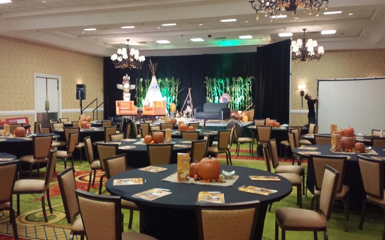 Corporate meeting room set with round tables and a staged presentation area
